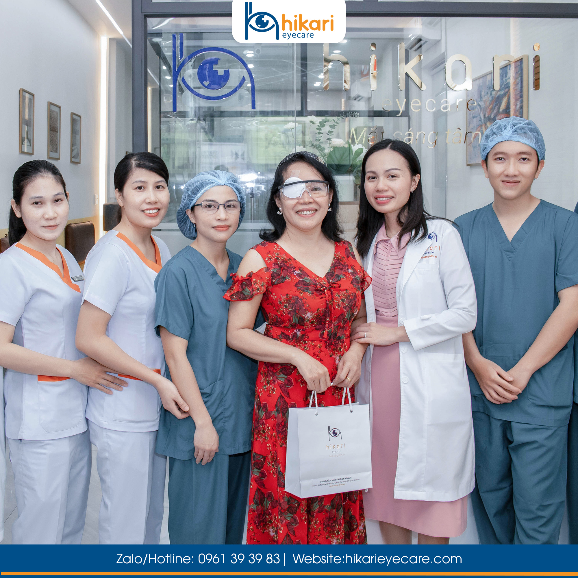 Bệnh nhân nữ đeo băng che mắt sau phẫu thuật chụp ảnh cùng bác sĩ và nhân viên y tế Hikari Eyecare