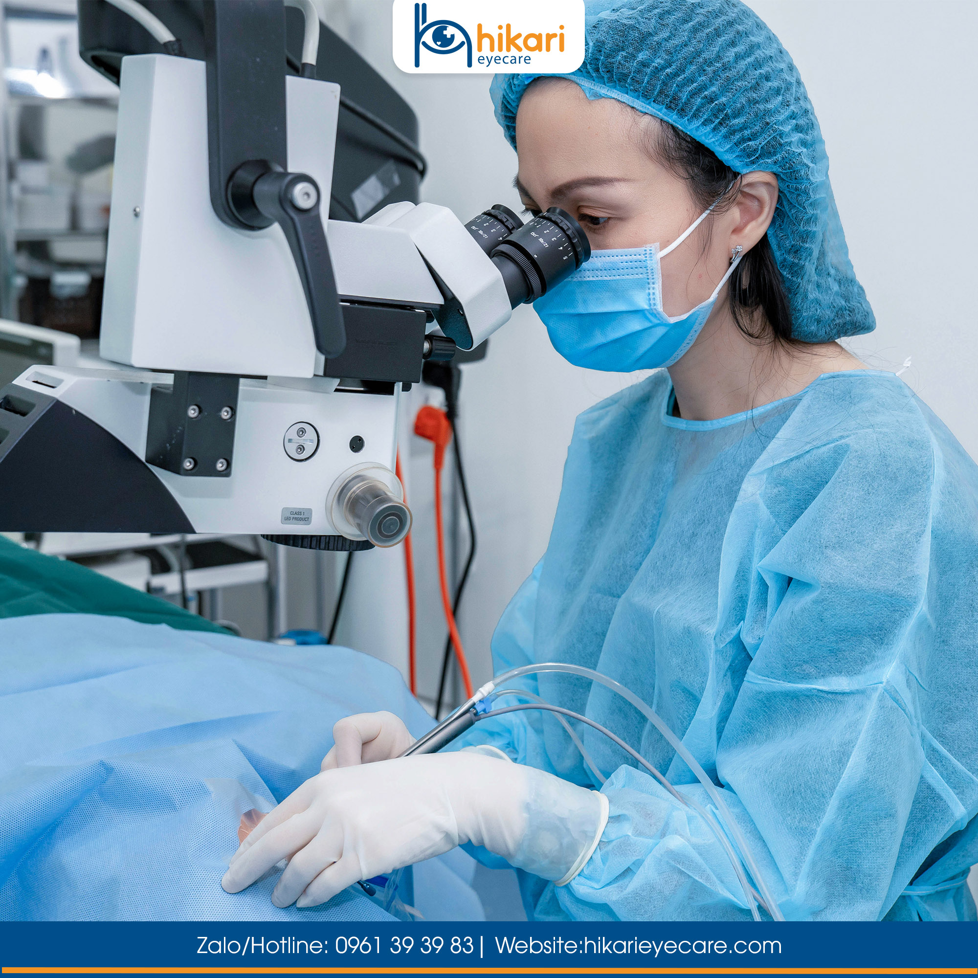 Bác sĩ nhãn khoa mặc áo phẫu thuật xanh đang thao tác qua kính hiển vi vi phẫu mắt